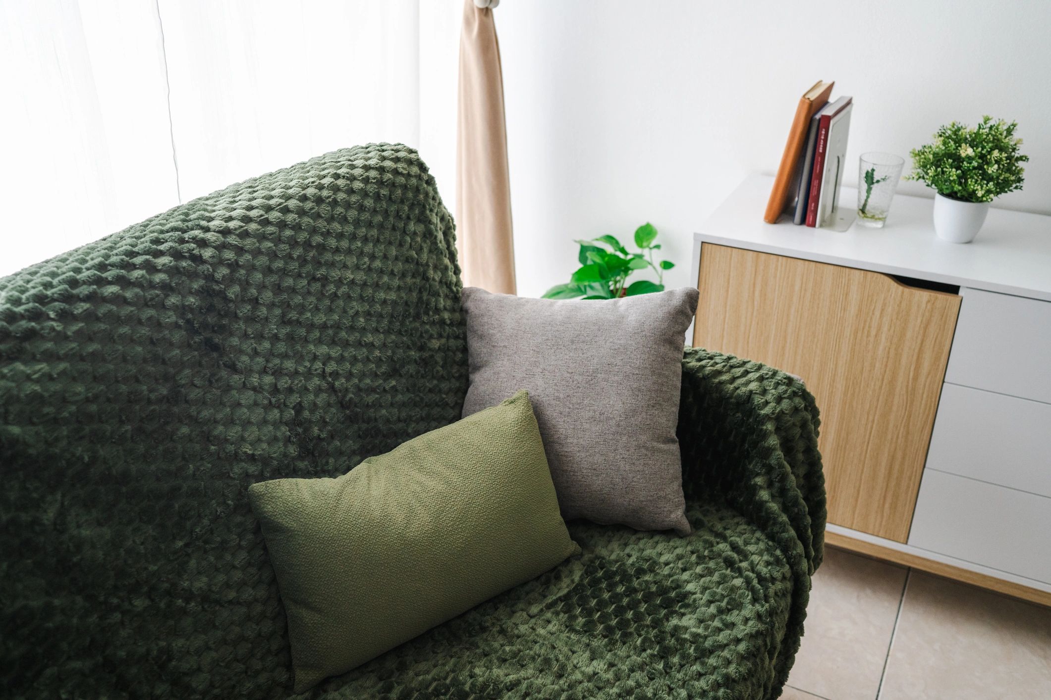 Minimalist living room with green sofa and cabinet